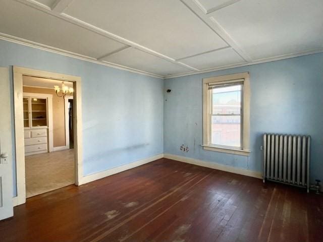 spare room featuring baseboards, an inviting chandelier, hardwood / wood-style flooring, and radiator