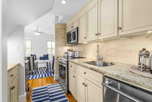 8 S St, Dennis, MA 02639 - kitchen with stainless steel appliances, a sink, a ceiling fan, decorative backsplash, and light wood-style flooring