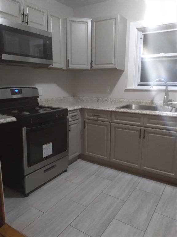 129 Marchand St, Fall River, MA 02723 - kitchen with appliances with stainless steel finishes, a sink, wood finish floors, and gray cabinetry