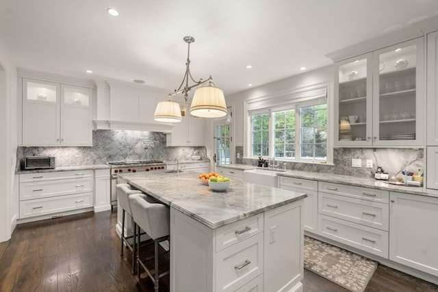 kitchen with a sink, tasteful backsplash, high end range, white cabinets, and recessed lighting