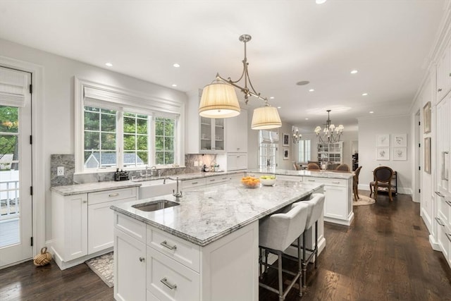 kitchen with a peninsula, a sink, a center island with sink, healthy amount of natural light, and recessed lighting