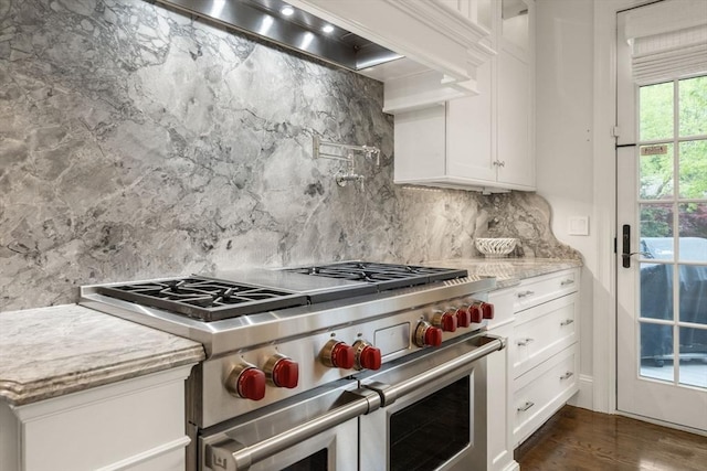 kitchen with double oven range, backsplash, white cabinets, dark wood-style floors, and light stone countertops