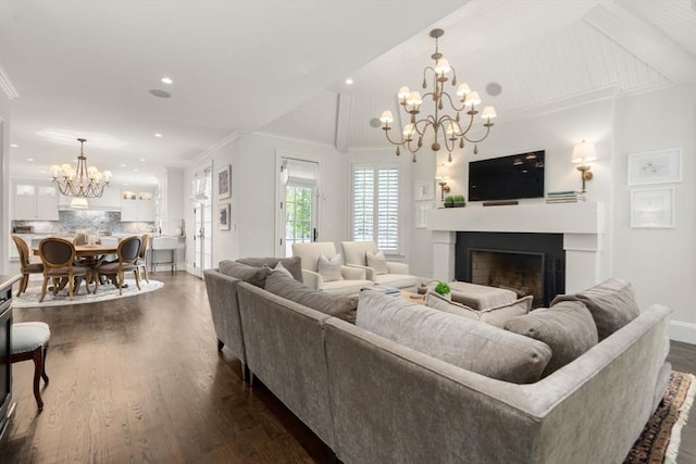 living room featuring a chandelier, a fireplace, dark wood-style floors, baseboards, and crown molding