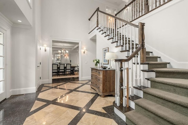 entryway featuring ornamental molding, inlaid floor details, stairway, a towering ceiling, and baseboards