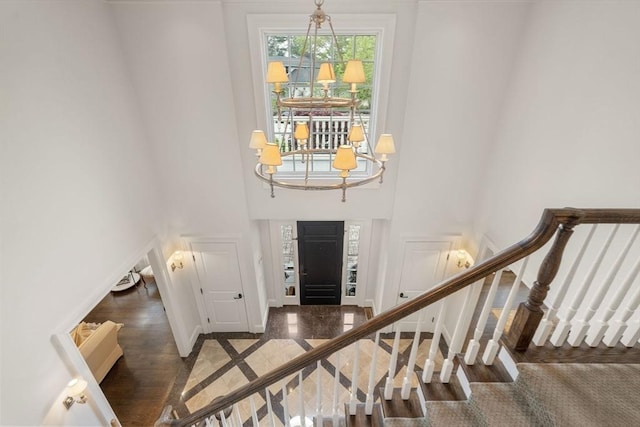 entryway featuring a towering ceiling, a chandelier, stairway, and baseboards