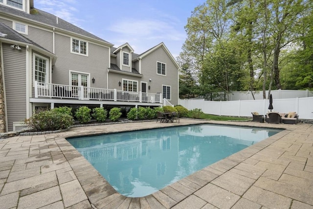 view of swimming pool featuring a patio area, a fenced backyard, and a wooden deck