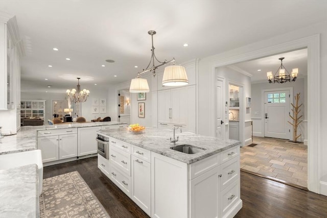 kitchen featuring a chandelier, a sink, recessed lighting, white cabinetry, and an island with sink