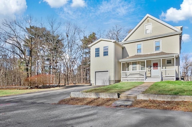 front of property with a porch, a garage, and a front lawn