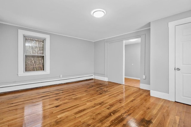 unfurnished bedroom featuring light hardwood / wood-style floors, baseboard heating, and crown molding