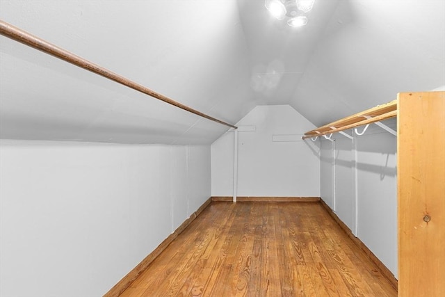 spacious closet with light hardwood / wood-style floors and lofted ceiling