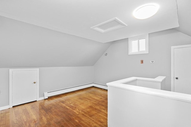 additional living space with wood-type flooring, vaulted ceiling, and a baseboard heating unit