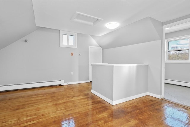 bonus room with wood-type flooring, lofted ceiling, and a baseboard heating unit