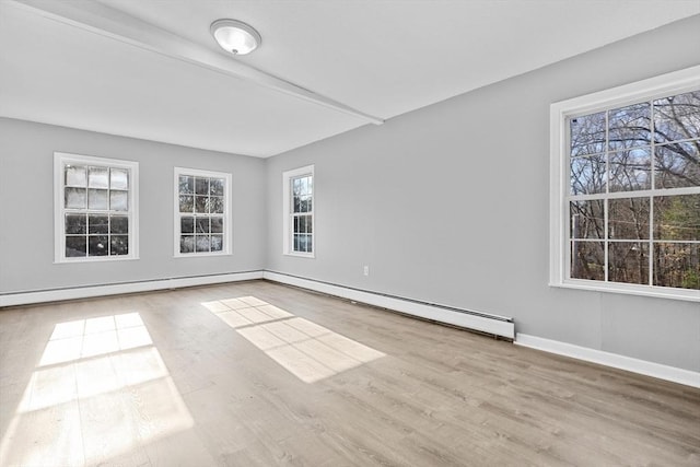 empty room featuring light hardwood / wood-style floors, a wealth of natural light, and a baseboard heating unit