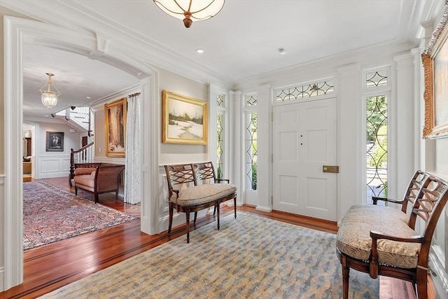 29 Willard Cmn, Concord, MA 01742 - entryway featuring wood finished floors, crown molding, a decorative wall, stairway, and a wainscoted wall