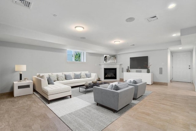 living room featuring recessed lighting, baseboards, visible vents, and a glass covered fireplace