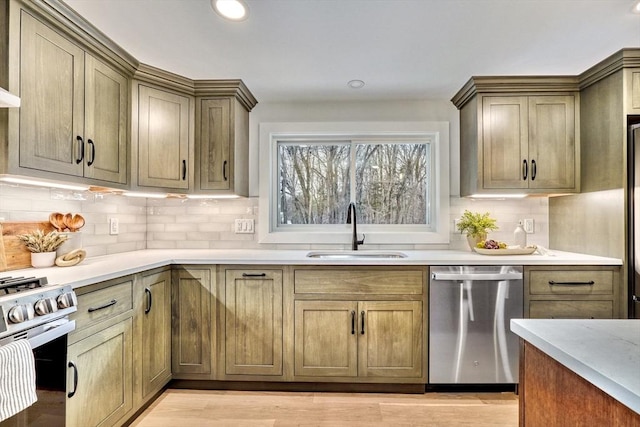 kitchen with appliances with stainless steel finishes, sink, backsplash, and light wood-type flooring