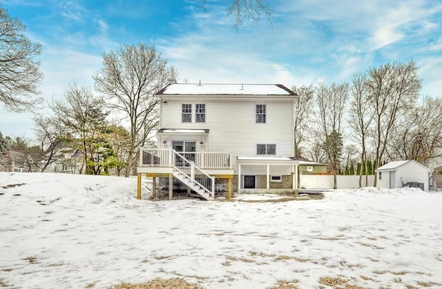 snow covered property with a shed and a deck