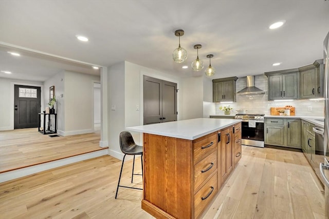 kitchen featuring decorative light fixtures, a center island, light wood-type flooring, stainless steel range, and wall chimney range hood