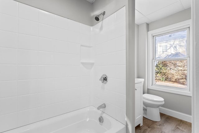 bathroom with baseboards, toilet, shower / tub combination, and wood finished floors