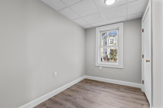 interior space with light wood-style floors, a paneled ceiling, and baseboards