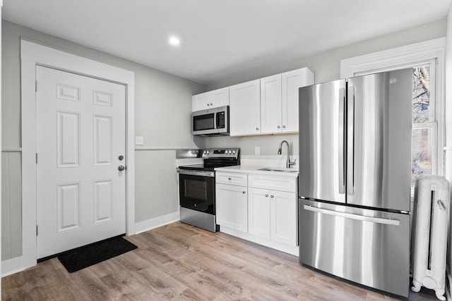 kitchen featuring a sink, white cabinetry, stainless steel appliances, and light countertops