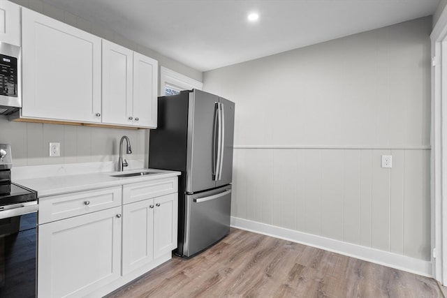 kitchen featuring white cabinetry, appliances with stainless steel finishes, light countertops, and a sink