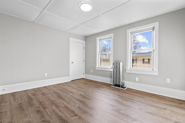 unfurnished room with radiator heating unit, wood finished floors, and baseboards