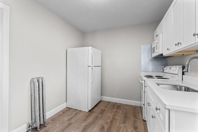 kitchen featuring light countertops, radiator heating unit, white cabinets, wood finished floors, and white appliances