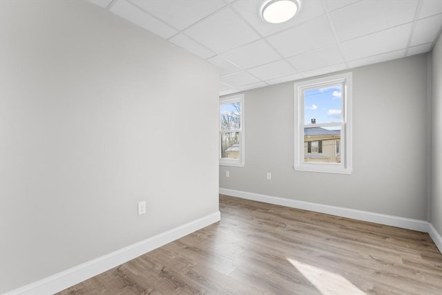 unfurnished room featuring light wood-type flooring, baseboards, and a drop ceiling