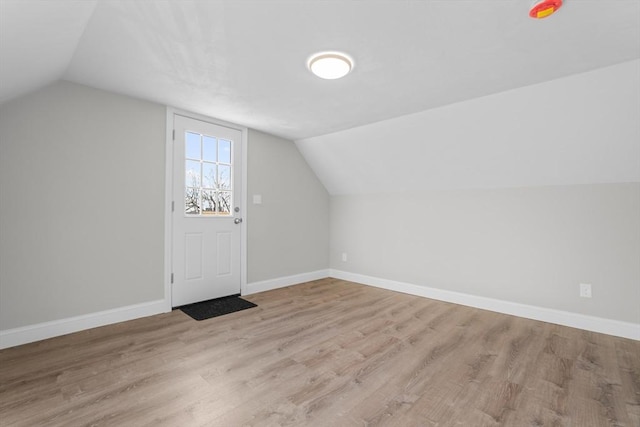 additional living space featuring light wood-type flooring, baseboards, and lofted ceiling