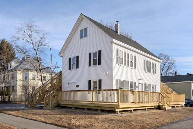 rear view of house featuring a deck, stairway, and a chimney