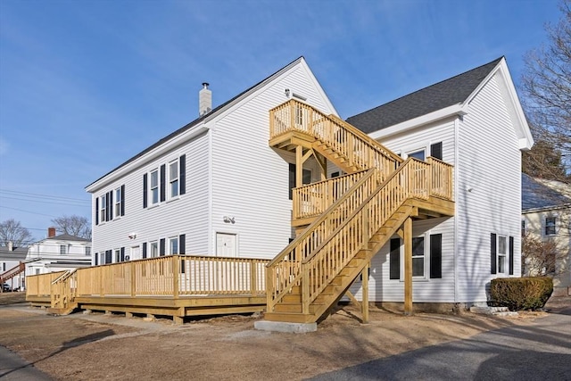 back of property featuring a chimney, stairway, and a wooden deck