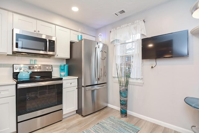 kitchen featuring decorative backsplash, stainless steel appliances, and white cabinetry