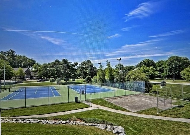 view of tennis court featuring a yard