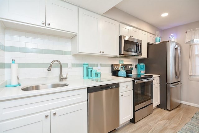 kitchen with sink, stainless steel appliances, light hardwood / wood-style flooring, decorative backsplash, and white cabinets