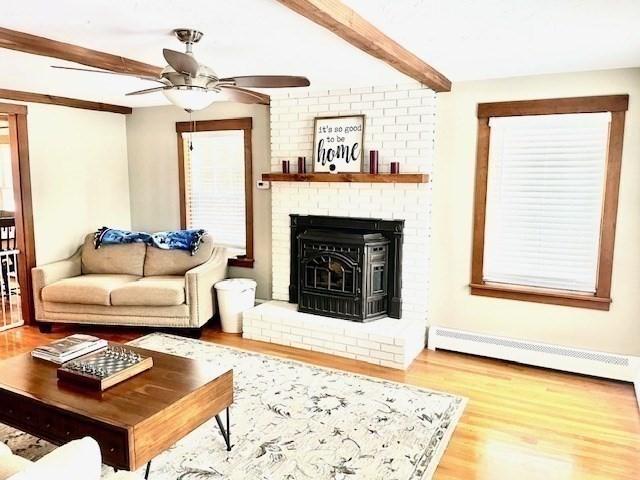 living area featuring a baseboard radiator, wood finished floors, beam ceiling, and a ceiling fan