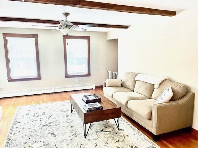 living area featuring beam ceiling, a baseboard radiator, radiator heating unit, ceiling fan, and wood finished floors