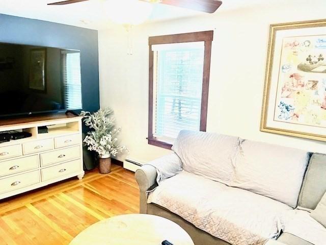 living room featuring ceiling fan, light wood-style flooring, and baseboard heating