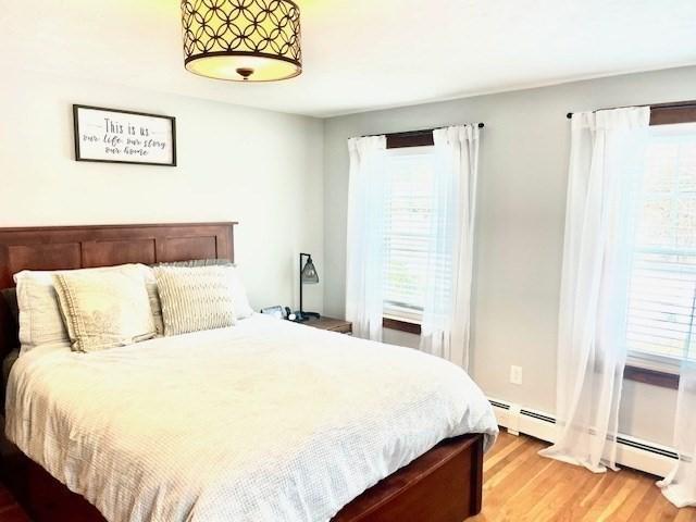 bedroom with baseboard heating and light wood-style flooring