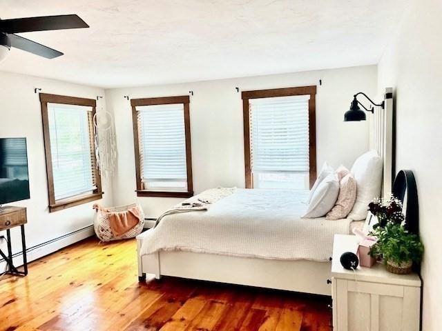 bedroom featuring a ceiling fan, a baseboard radiator, and wood finished floors