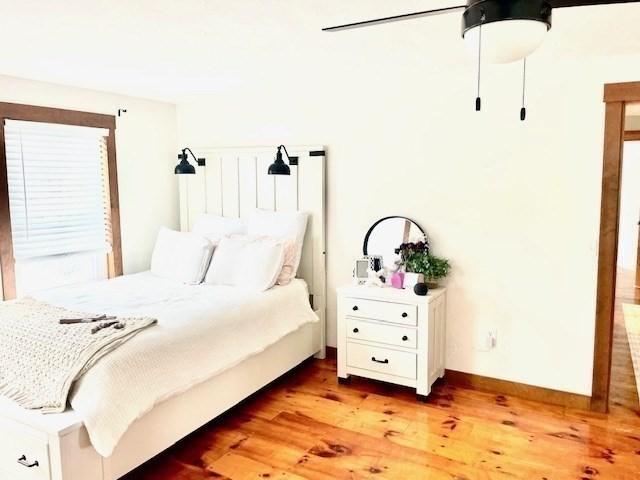 bedroom featuring baseboards, ceiling fan, and light wood finished floors