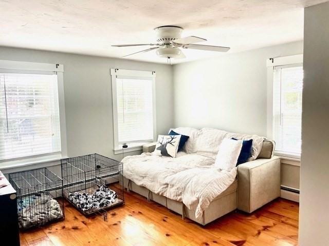 living area featuring ceiling fan, baseboard heating, and wood finished floors