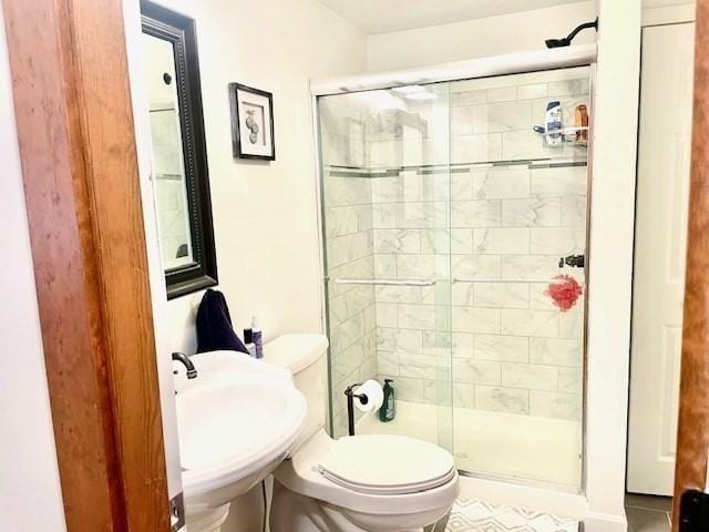 bathroom with a stall shower, a sink, and toilet