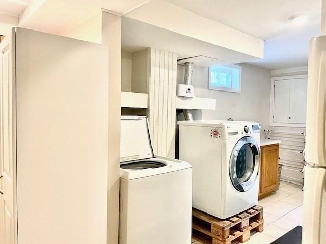 washroom with independent washer and dryer and light tile patterned floors