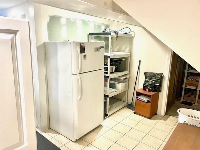 kitchen with light tile patterned floors and freestanding refrigerator