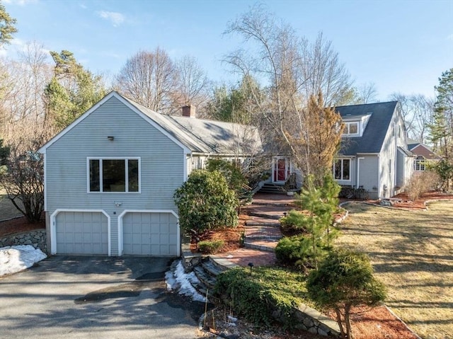 view of front of house featuring aphalt driveway, an attached garage, and a chimney