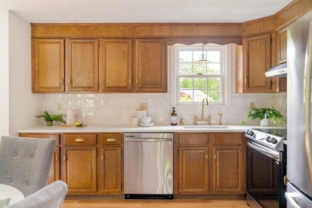 50 Hillside Rd, Tewksbury, MA 01876 - kitchen featuring stainless steel appliances, a sink, under cabinet range hood, brown cabinets, and light countertops