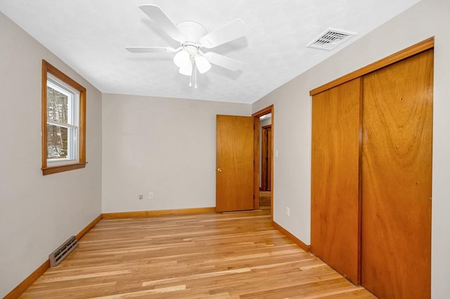 unfurnished bedroom with ceiling fan, a closet, and light wood-type flooring