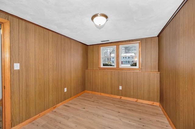 empty room featuring wood walls and light hardwood / wood-style flooring