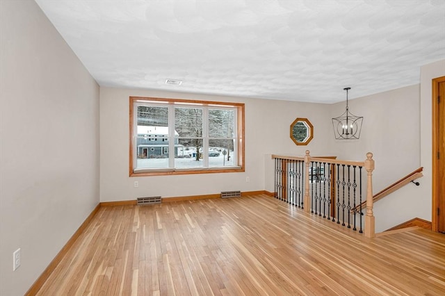 spare room with hardwood / wood-style floors and a notable chandelier